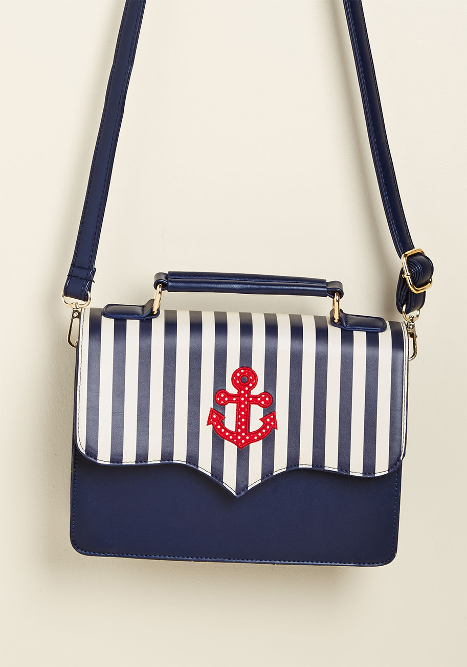 BG7255 - There's no denying the seaworthy swagger of this crossbody bag from Banned! Classic cream stripes and a red, dotted anchor play up the sailing motif of this faux-leather purse, while gleaming gold hardware, a spacious interior, and a handy compartment opp