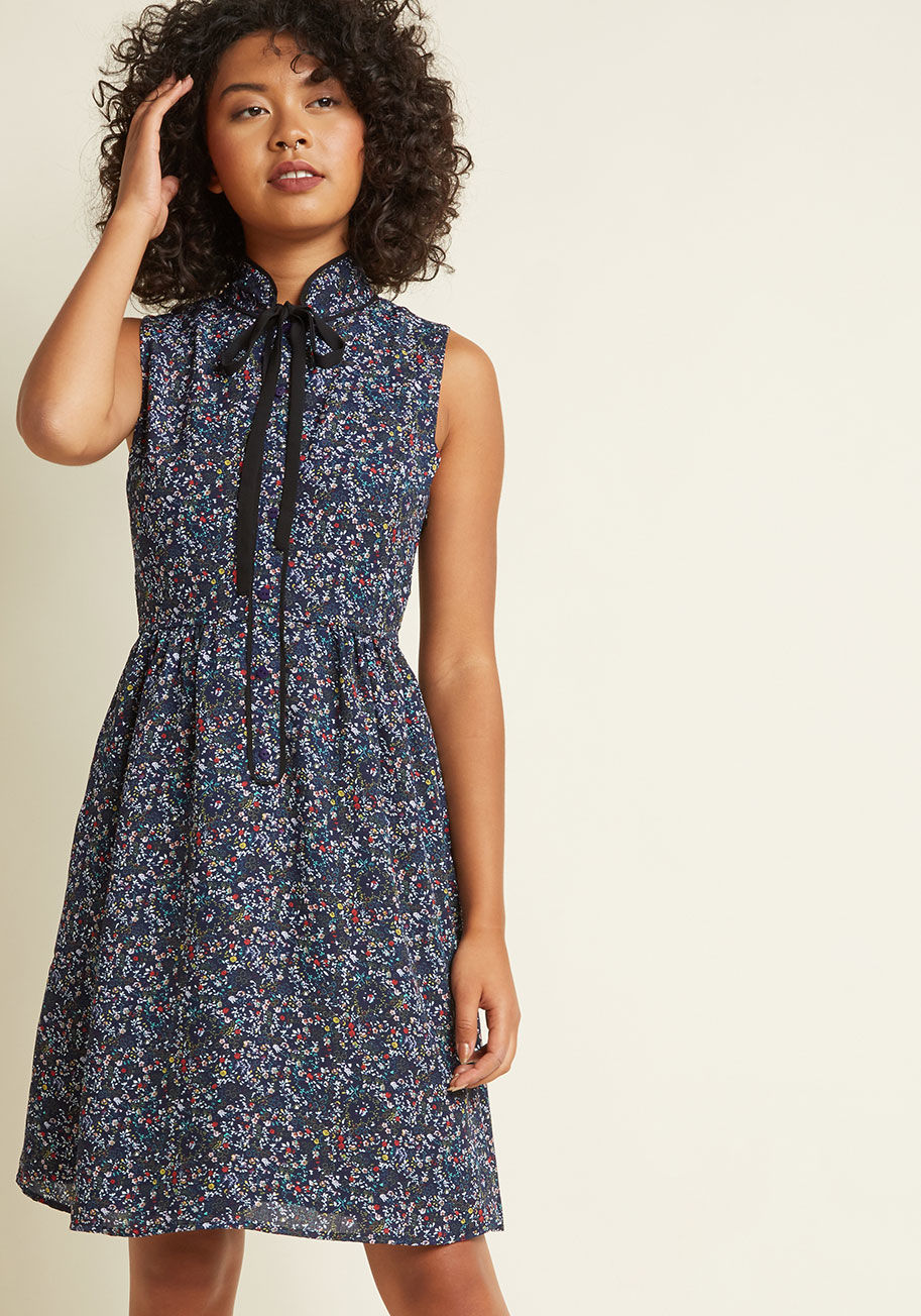  - Even when there's only moments to craft an outfit, you emerge feeling your very best with this navy blue dress time and again! In addition to a solid black neckline tie, this ModCloth-exclusive frock offers its buttoned placket and whimsical wildflower pr
