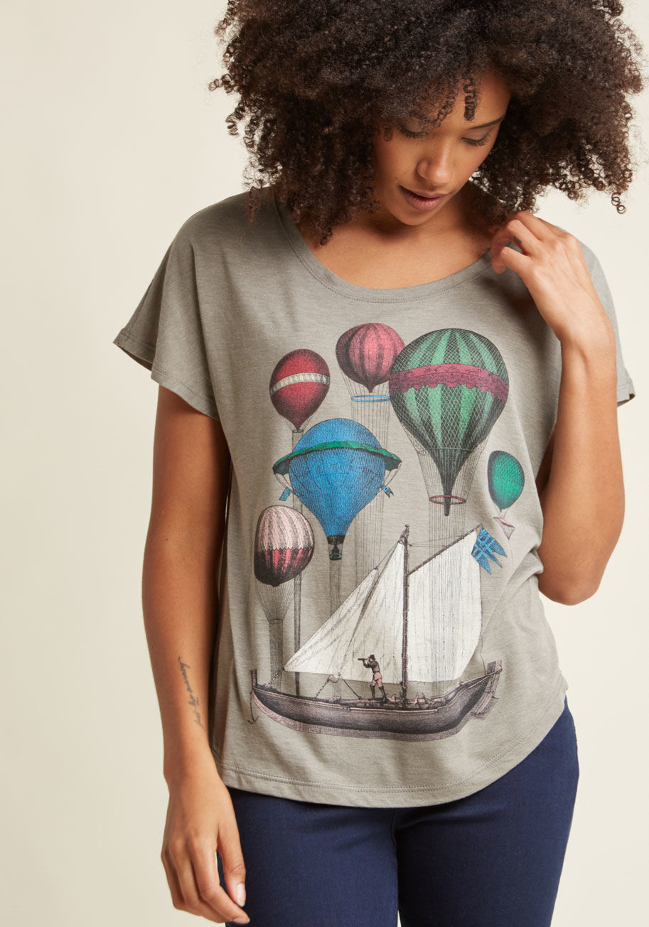  - Inspiration for your next great trek is right under your nose - well, it is while you're wearing this grey T-shirt! Jewel-toned hot air balloons keep a sailboat adrift rather than afloat on top of this relaxed-fit tee, serving as a reminder to approach yo