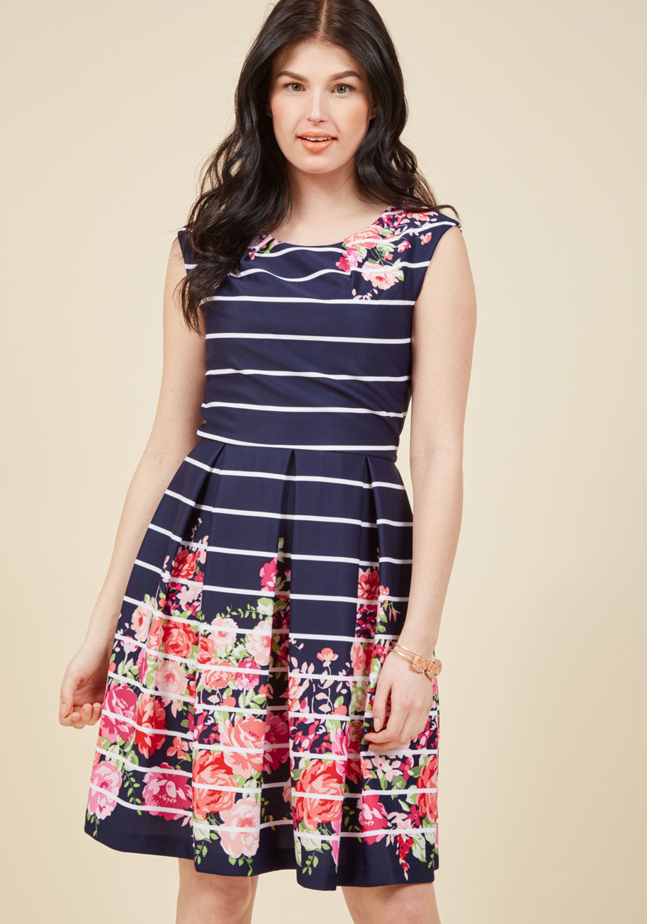 - Oh how beautiful flowers just fill your heart with joy! This navy blue dress exhibits a pink, coral, red, and magenta arrangement of petals streaked with stripes of white light as if peeking through shutters. Accented with a V-back and a primly pleated wa