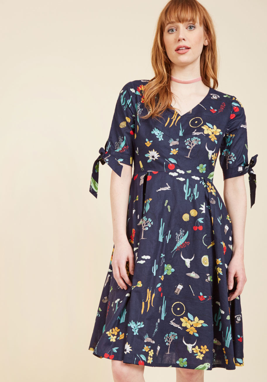  - Twirling into this navy blue dress is like spinning into a menagerie of merry imagery! The eclectic pattern of this V-neck frock features everything from birds and bunnies to peanuts and peppers, to French presses and phones. Fun! Not to mention, the tied