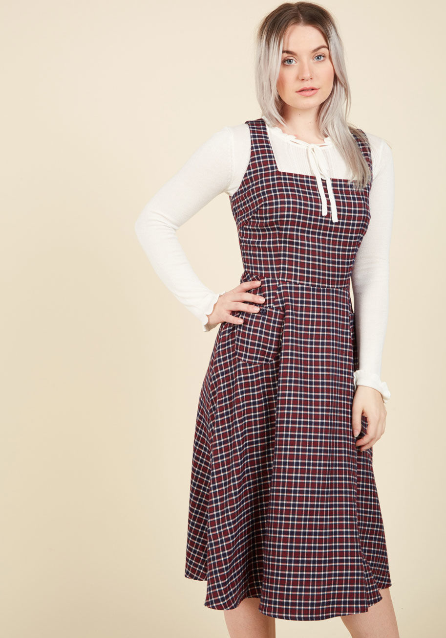  - Why dream of romantic scenes from bygone times when this plaid dress from Collectif allows the style of the era to live on through you? Nostalgically detailed with navy buttons down the side, a pair of pockets, and navy and white squares, this maroon pina