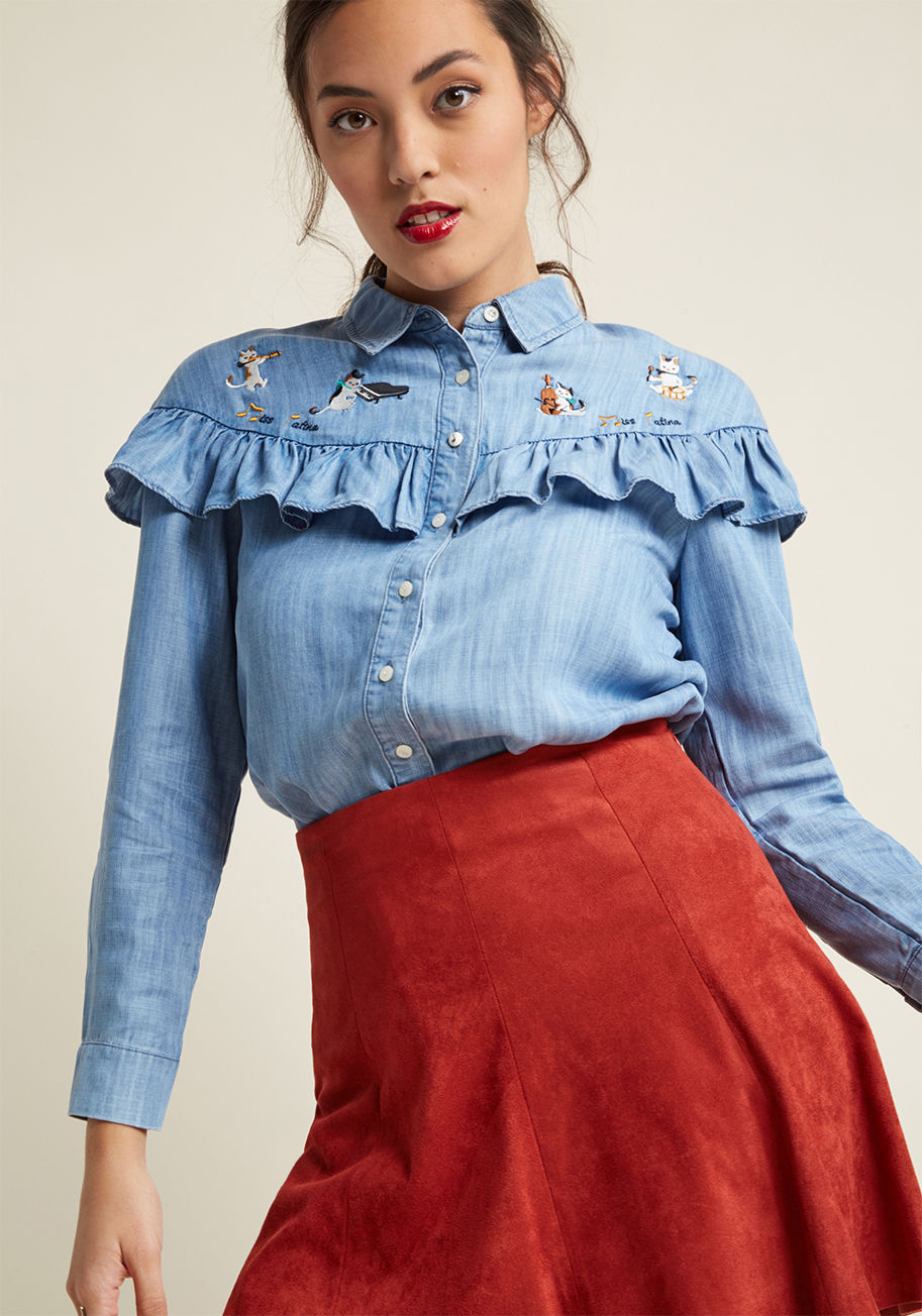 17AW-SHT-06 - Introduce a symphony of style into your ensemble with this chambray shirt by Miss Patina! This side-vented top has the bones of a classic button up, enhanced by the addition of a cross-chest ruffle, standout enamel music note button, and band of embroider