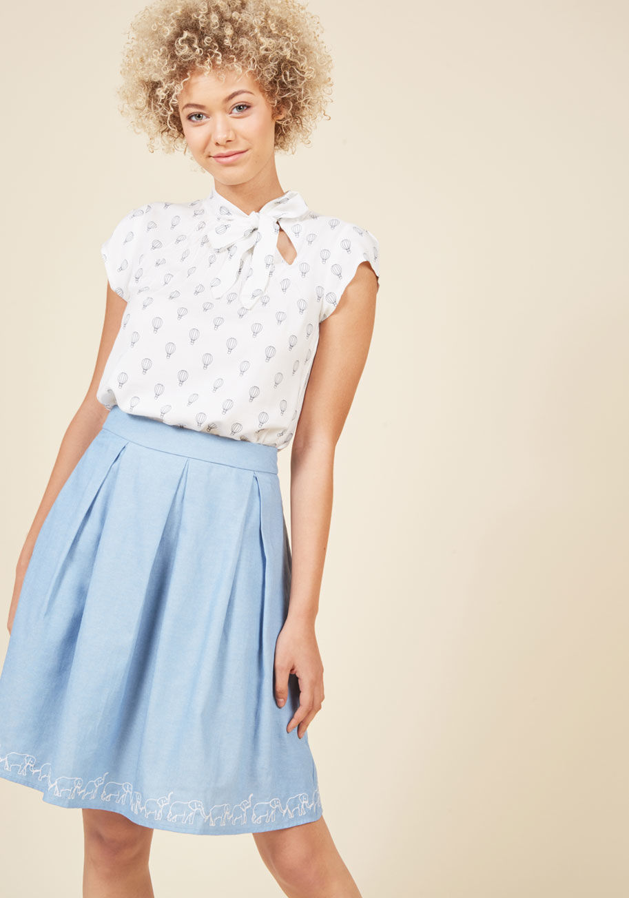 CB-115 - It&rsquo;s a bird! It&rsquo;s a plane! No, it&rsquo;s the lofty and lovely feeling inspired by this white blouse! Navy blue, vintage-inspired hot air balloons take flight atop this cap-sleeved top, while a neck tie and pintucking elevate your look to new 