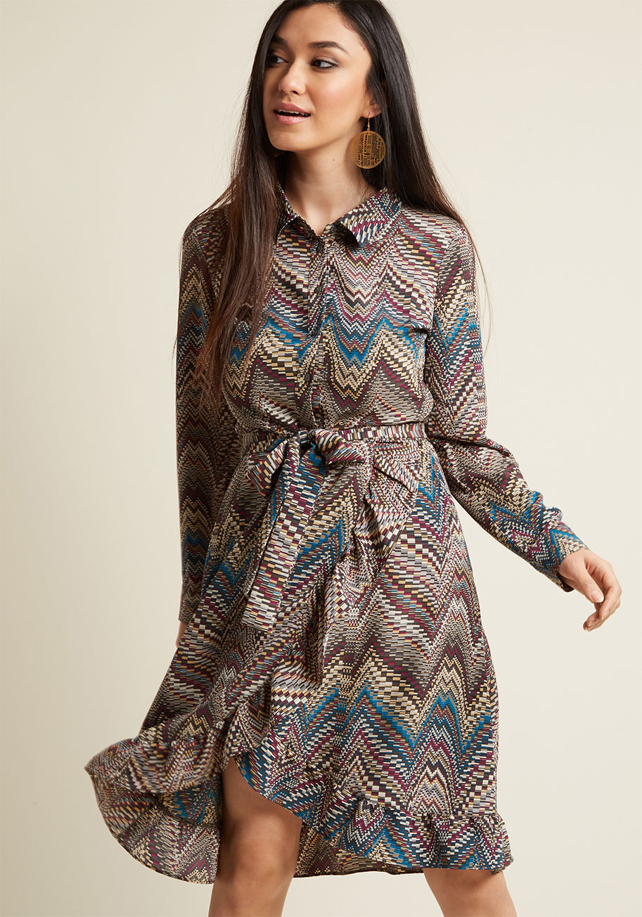 D-61245 - This printed dress employs two beloved silhouettes - the wrap dress and the shirt dress - to create one stunning garment! A ModCloth exclusive, this woven frock is filled to the brim with flattering and fun details, from its matching sash and ruffled skir