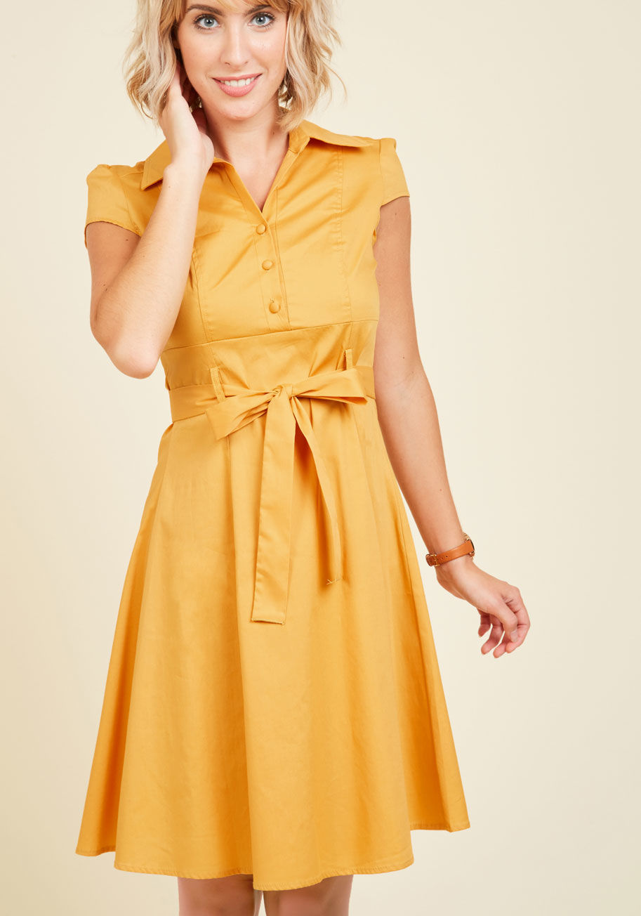 D1530-1 - In this &lsquo;50s-inspired shirtdress, your date at the ice cream parlor is a stylish one! The bright goldenrod hue, fabric-covered buttons, and slight stretch to the cotton blend of this eye-catching dress make it a cute wear