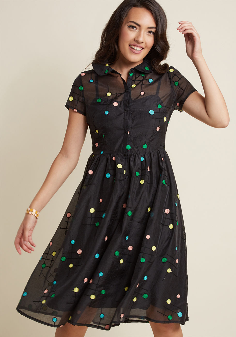Oh, the incredible difference a few colorful dots can make! On its own, this black shirt dress is simply darling with its short sleeves, sheer overlay, and midi length. However, the addition of yellow, green, pink, and blue embroidered spots transform thi by DRA8409