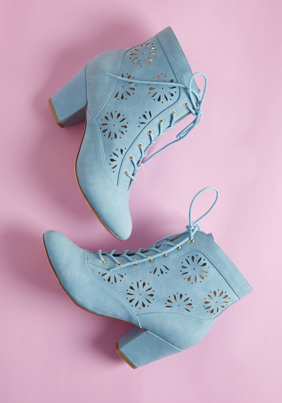With the grace of a petal landing lightly on the grass, your gait adopts a new elegance through these sky blue booties from B.A.I.T. Footwear. Gold eyelets gleam against the matte uppers of this block-heeled pair, while floral medallion cutouts and dotted by HELOISE