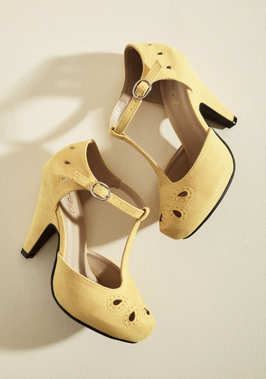 MCDD 1-6W - Team these playful yellow T-straps up with your dynamic dance moves and watch as magic unfolds! The tapered heels, teardrop-shaped cutouts with perforated accents, and faux-suede finish of this ModCloth-exclusive pair all put an oomph into your outfit tha