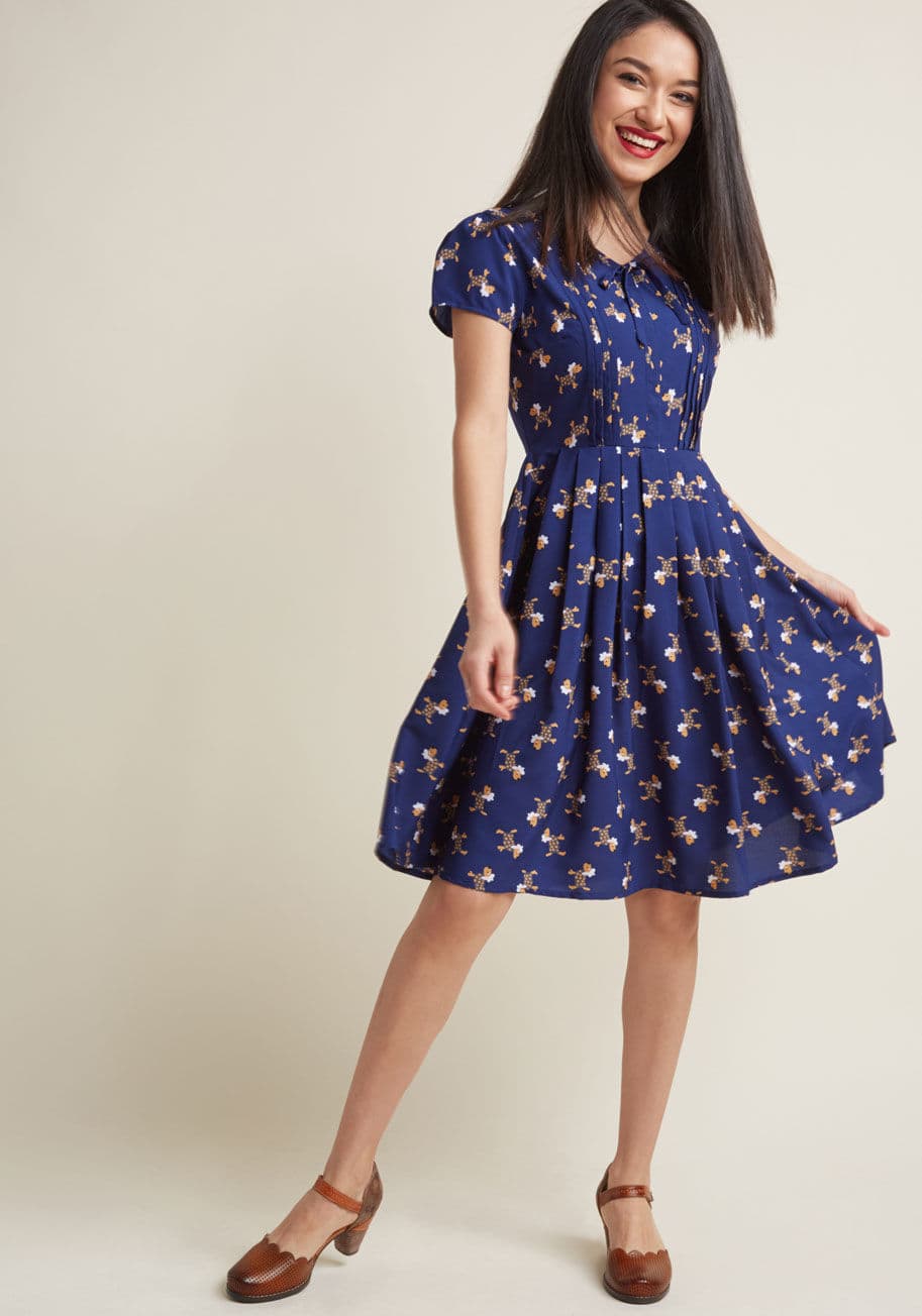 Those seeking unique details to freshen up their wardrobe will go wild over this navy A-line dress! Though its bow-topped V-neckline and pleated skirt can be considered classic accents, its pintucked bodice and quirky Parisian pup pattern take it to a new by MDD1134A