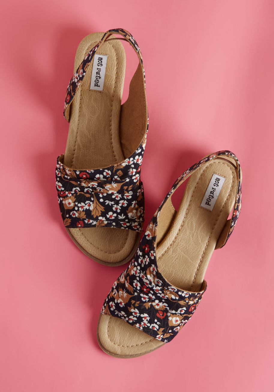 Finding supporters for these slingback sandals is a simple task, indeed! Pleated uppers, a navy floral pattern, and micro wedges all do their part by Shanna