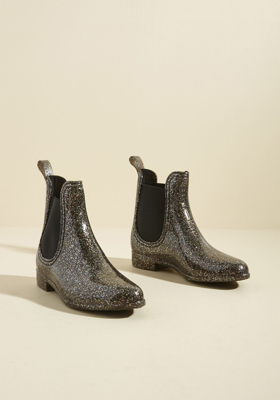 Slicker2 - Put some pizzazz into your puddle jumping with these sparkly rain boots by Report Footwear! Fusing a chic silhouette and black stretch panels with playful layers of silver, gold, and magenta glitter, this rubbery, vegan-friendly pair adds gleaming panache