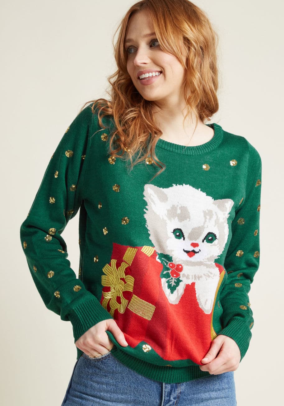 A surprise appearance from a relative, pal, or furry friend is always a gift, and this forest green sweater puts that concept on charming display! Boasting an intarsia kitten, metallic gold embroidery, and clusters of sparkly sequins all over, this fierce by TE-CWSW160